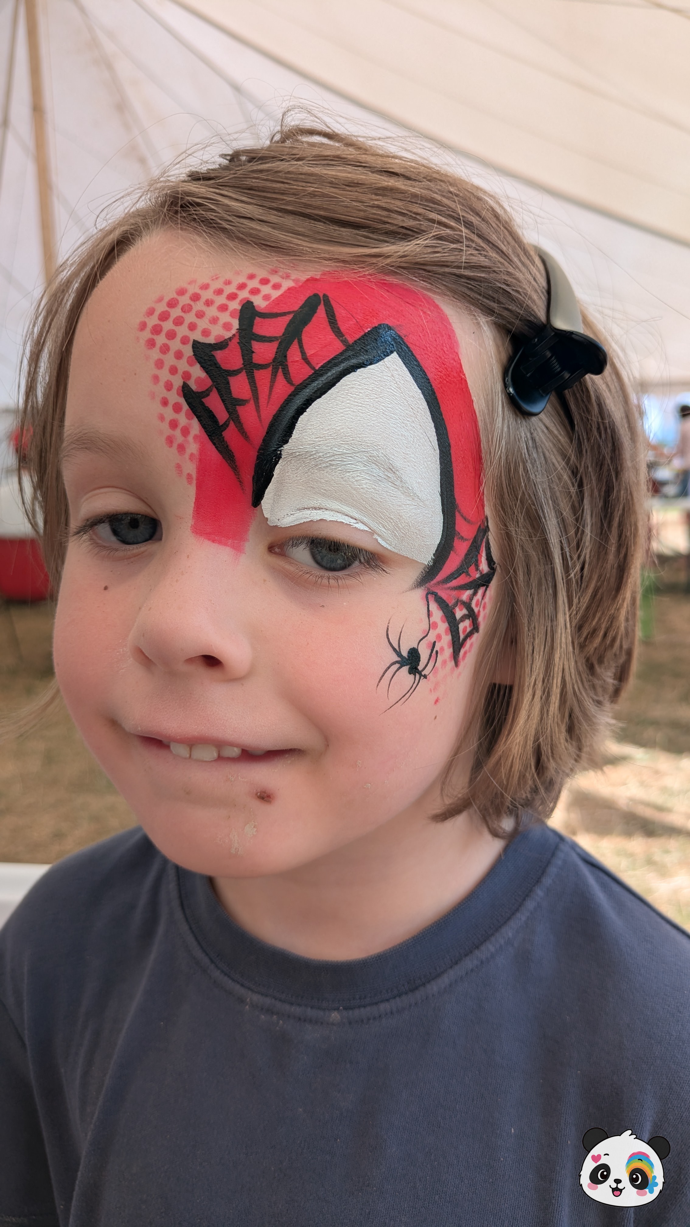 Red and white comic-style spider hero mask face paint with black web details and a small spider on the cheek.