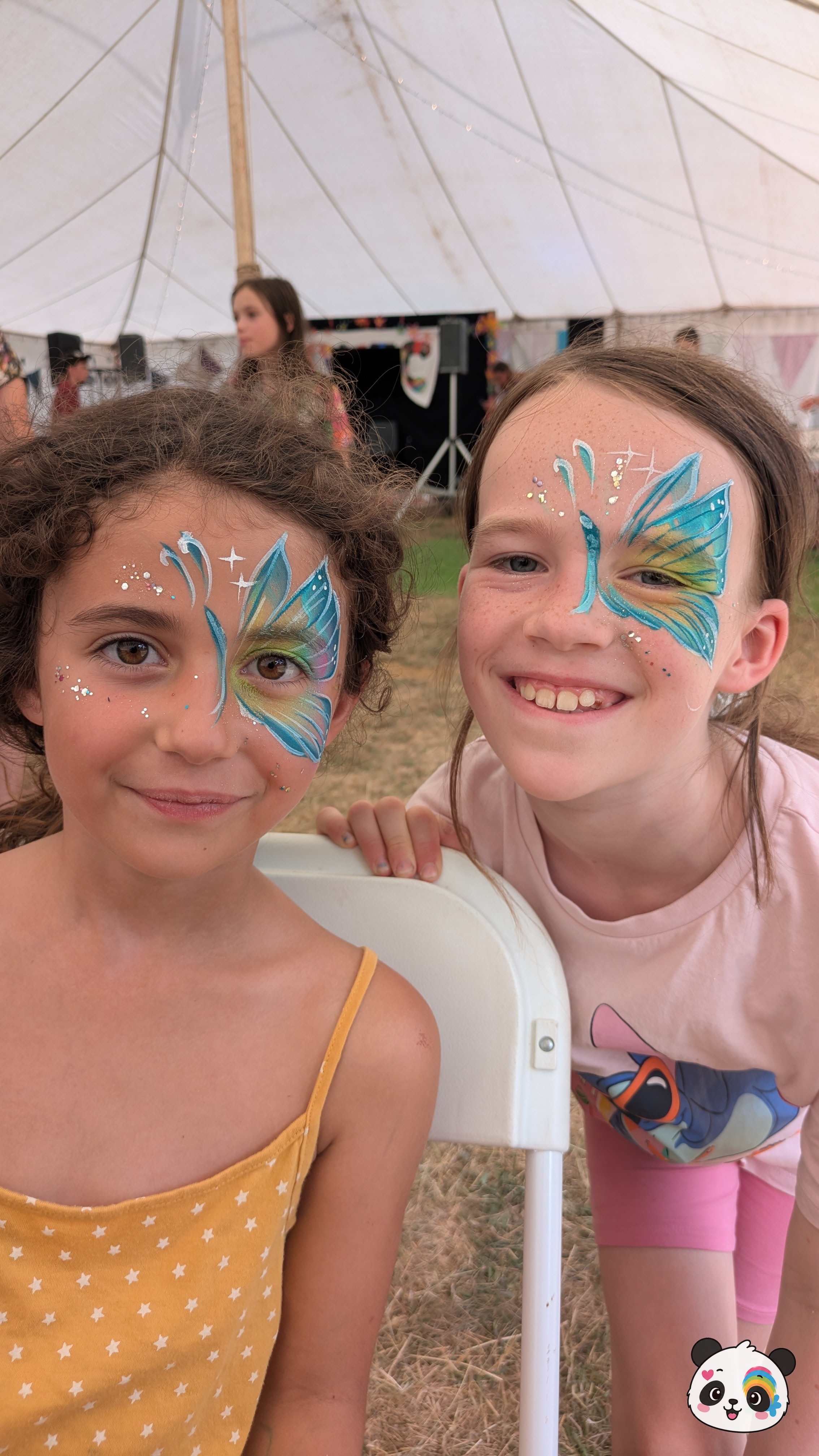 Blue and yellow butterfly wing face paint designs with white star accents and glitter, applied to the eyes and temples.