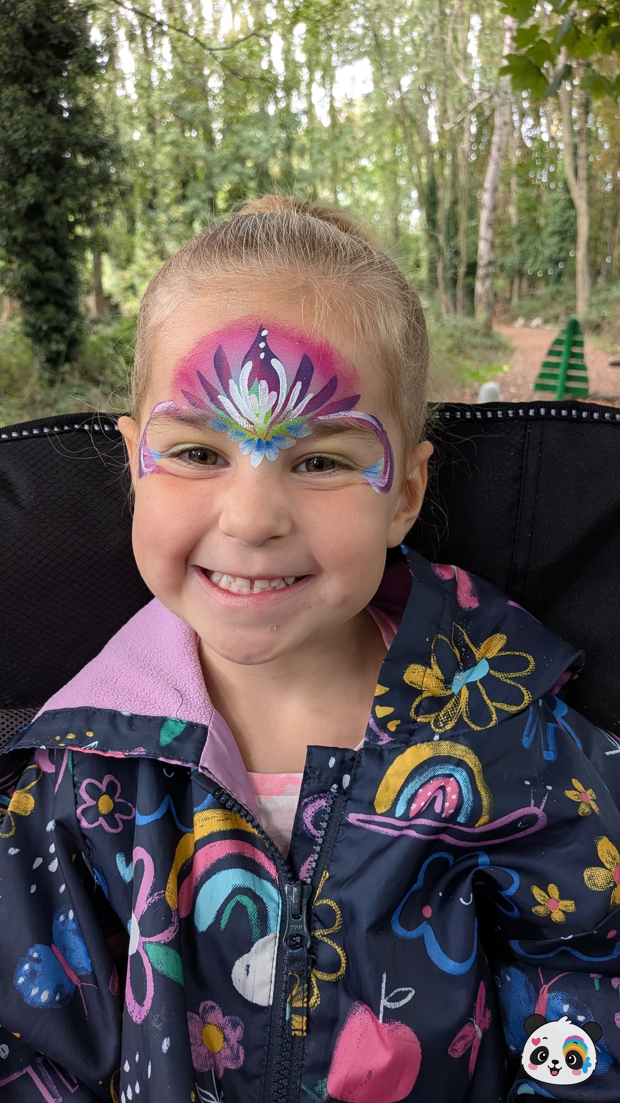 A purple, pink, and white lotus flower design painted across the forehead with delicate swirls extending towards the temples.