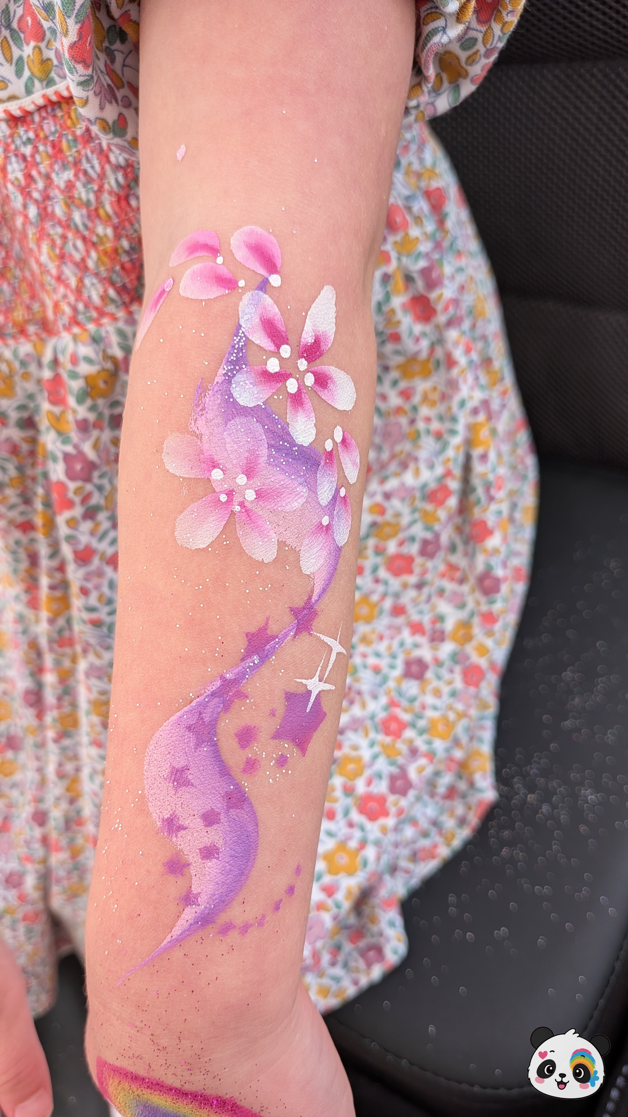 Pink and purple floral design with star accents and glitter on an arm.