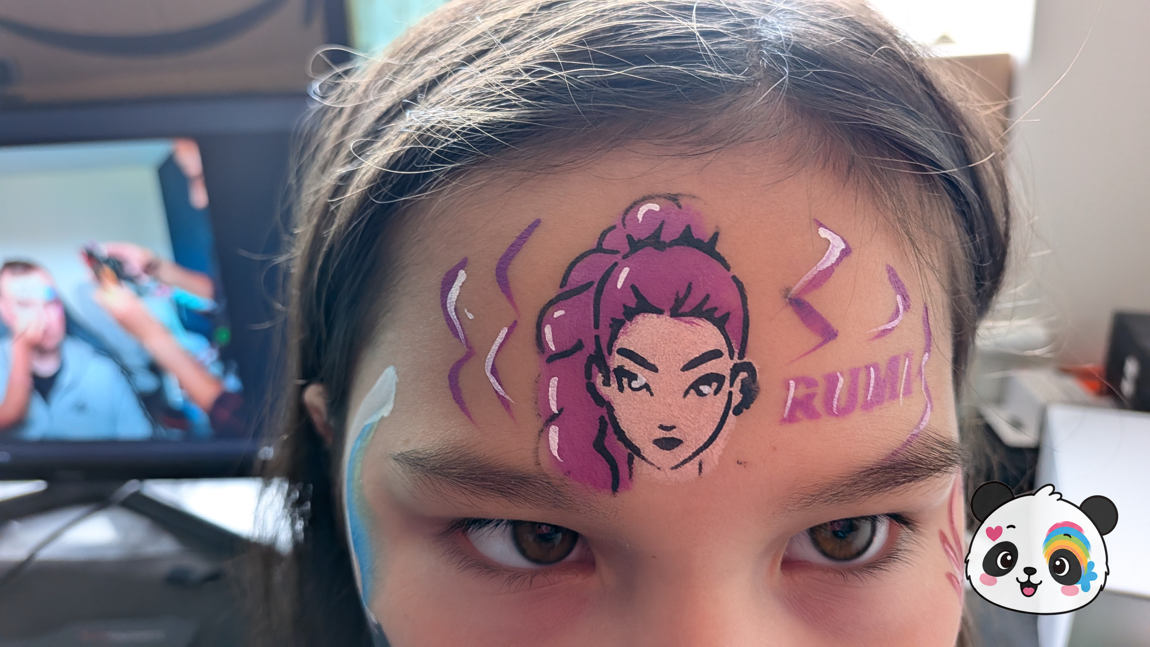 Forehead face paint featuring a stylized anime-style character with purple hair, accented by purple lightning bolts and the name Rumi.