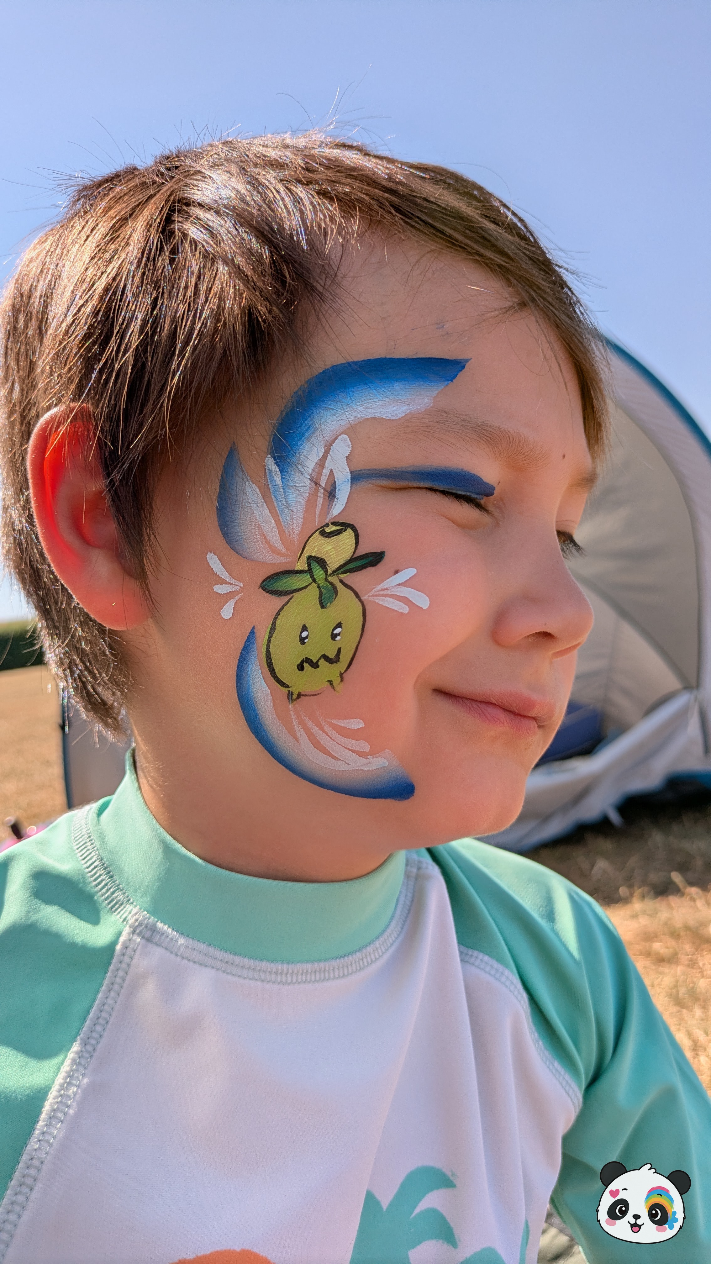 A green cartoon olive character with a face painted on the cheek, surrounded by blue and white swooshes and white wing-like accents.