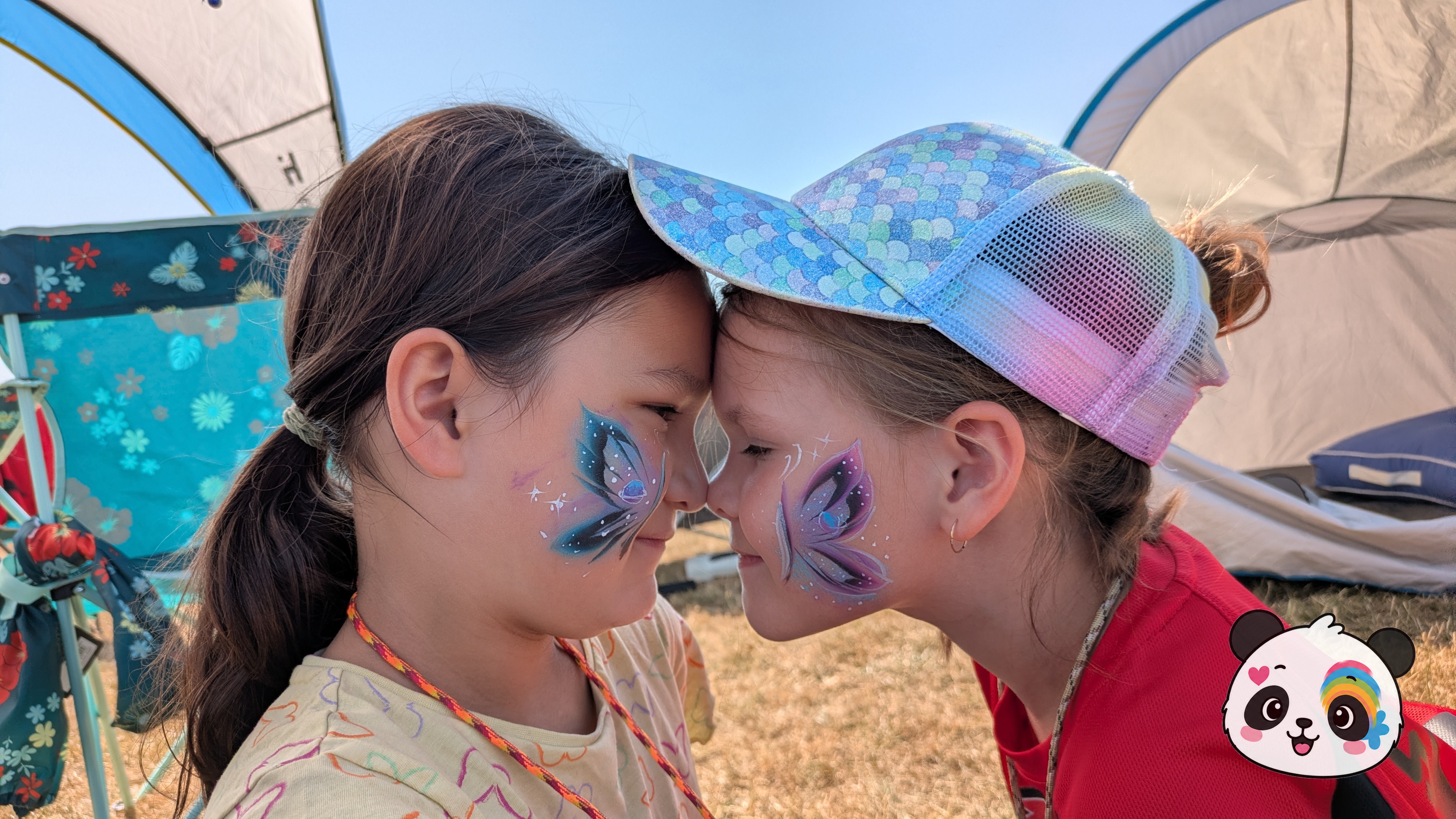 Two butterfly face paint designs in blue, purple, and white, each painted on the cheek of a person.