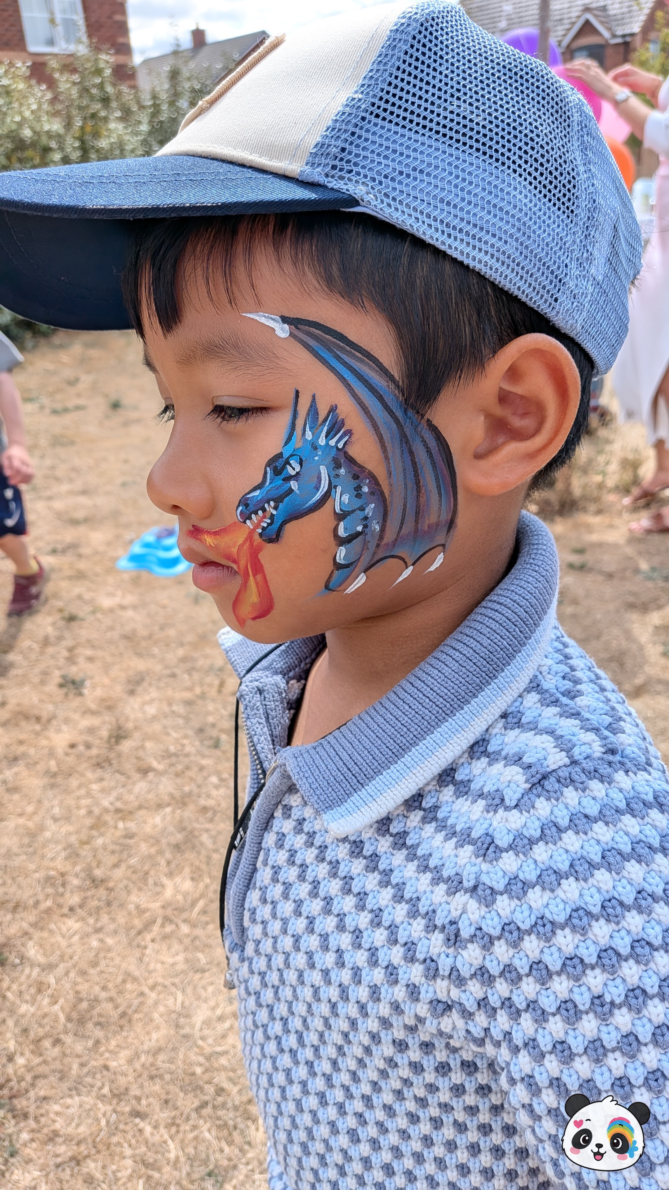 Blue dragon face paint with orange and yellow flames on the cheek