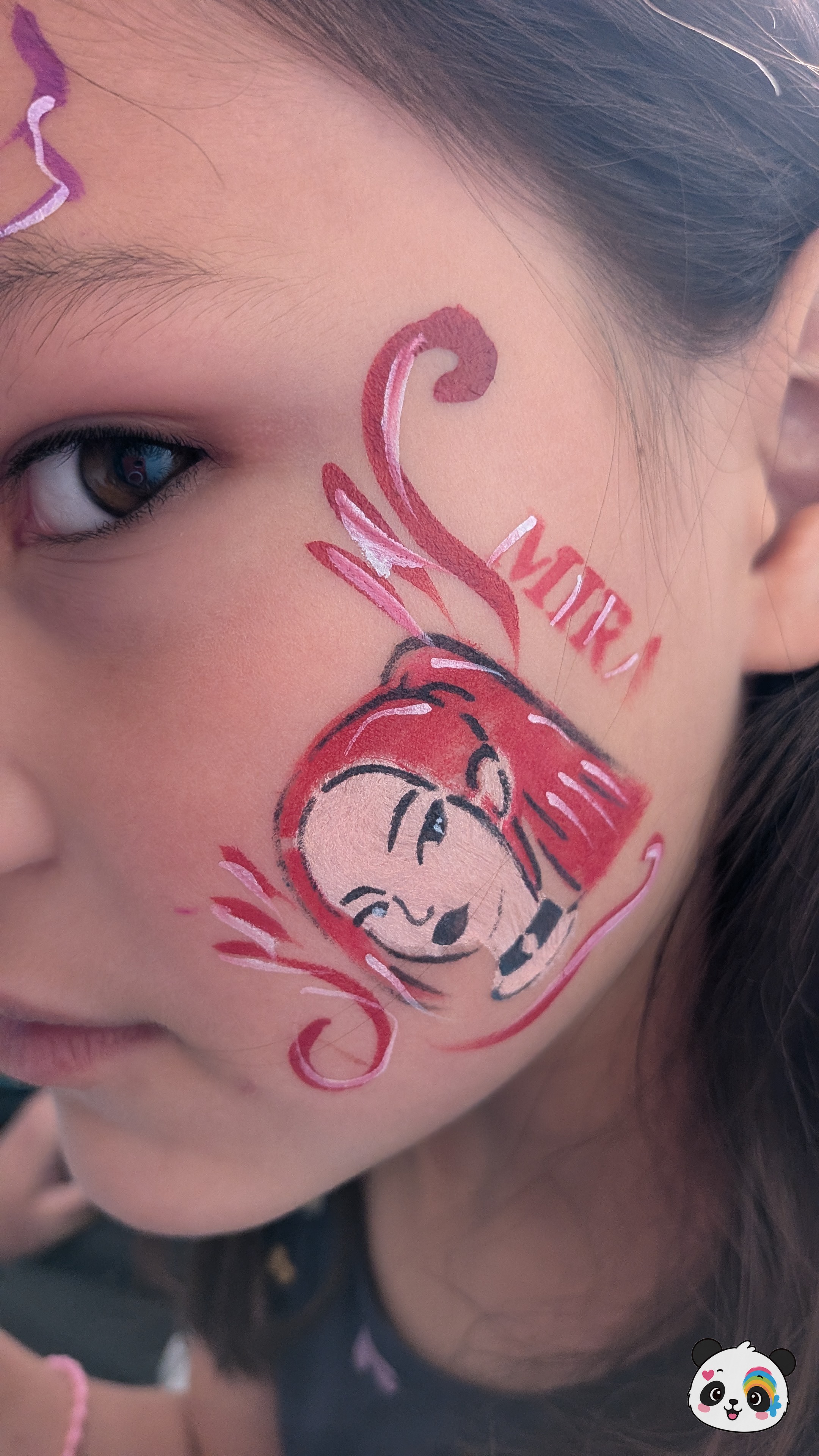 Red and pink anime-style character portrait painted on the cheek with decorative swirls and lettering.