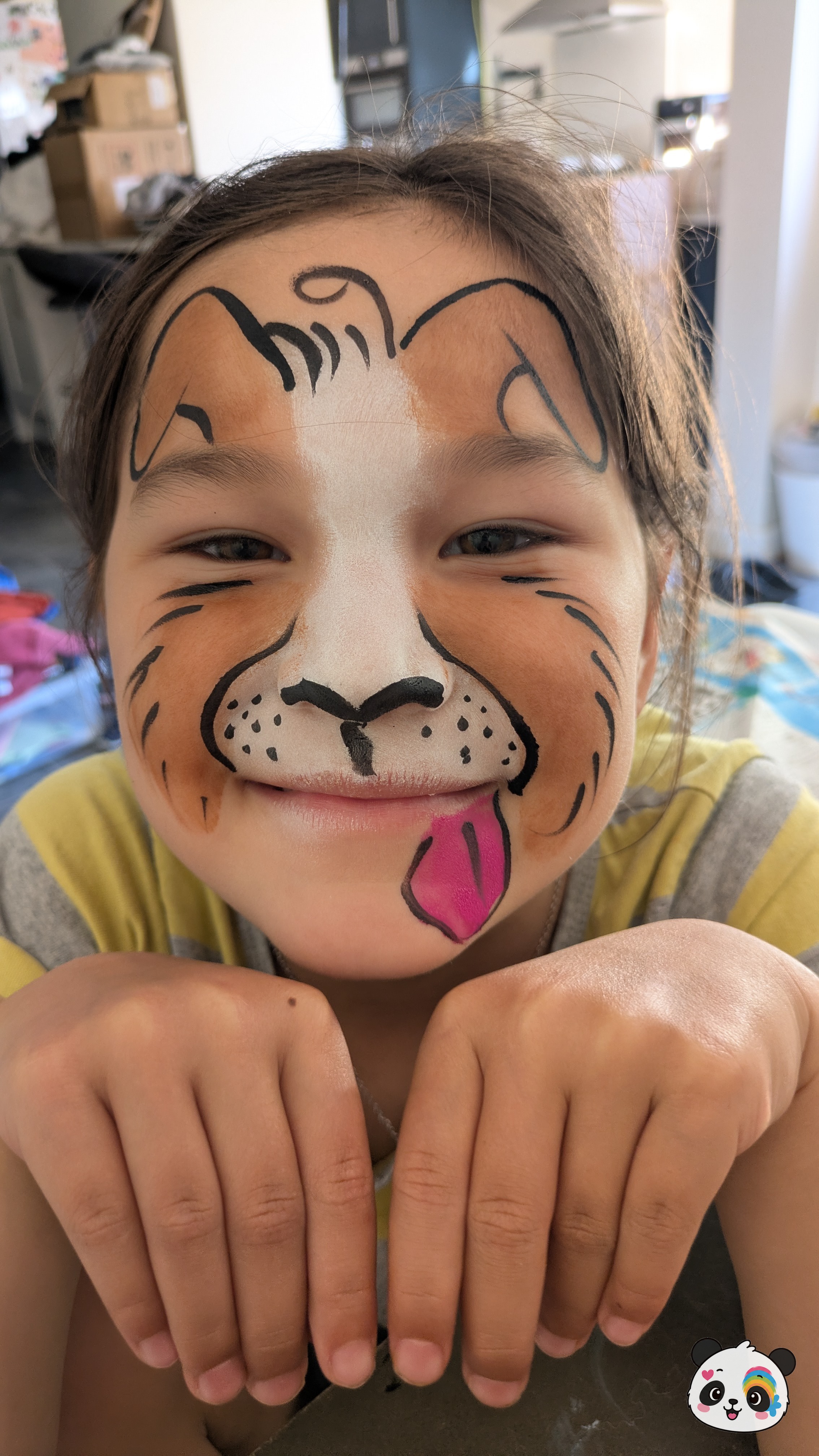 Brown and white puppy face paint with black outlines, whiskers, and a pink tongue sticking out on the chin.