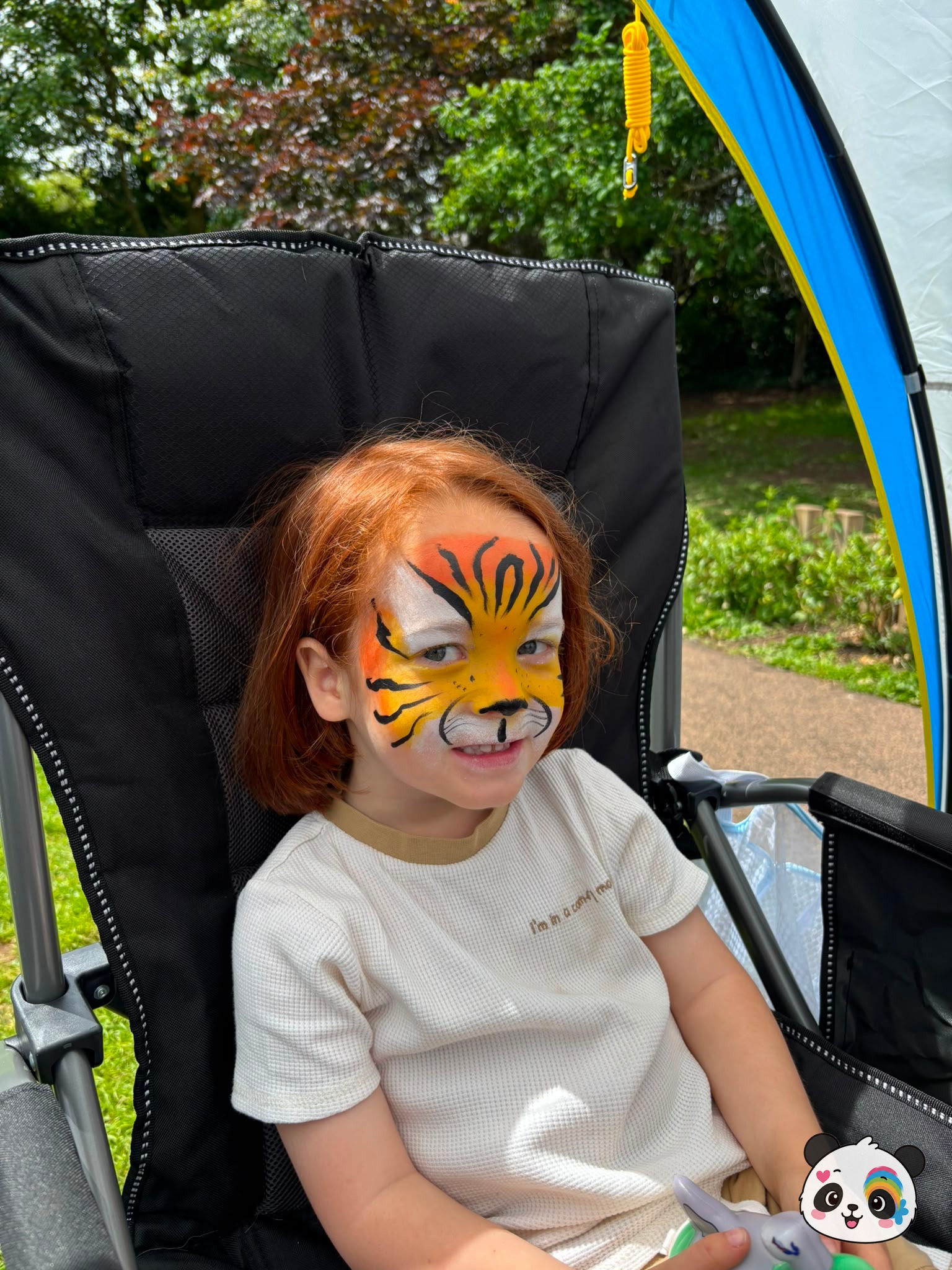 Orange, yellow, and white tiger face paint with black stripes covering the forehead and cheeks.