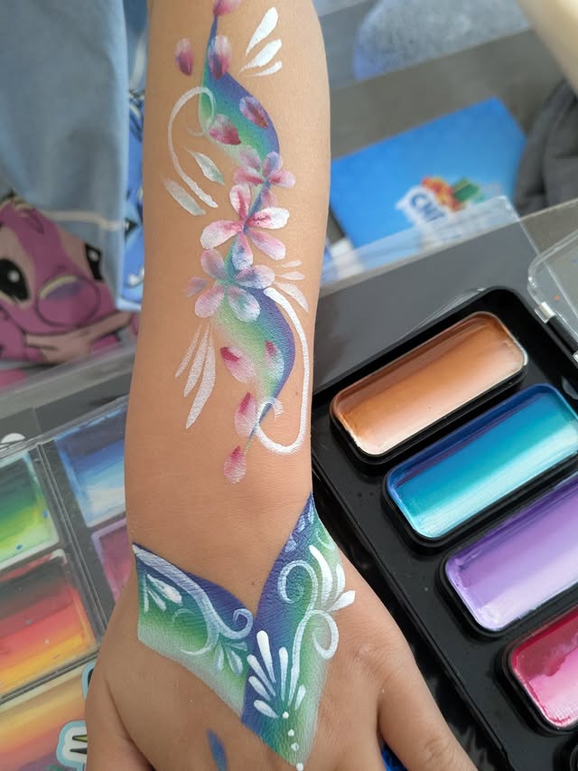 Teal and purple floral arm painting with butterfly-style hand art