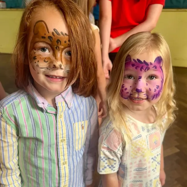 Two children with leopard and cheetah face paint at an indoor event