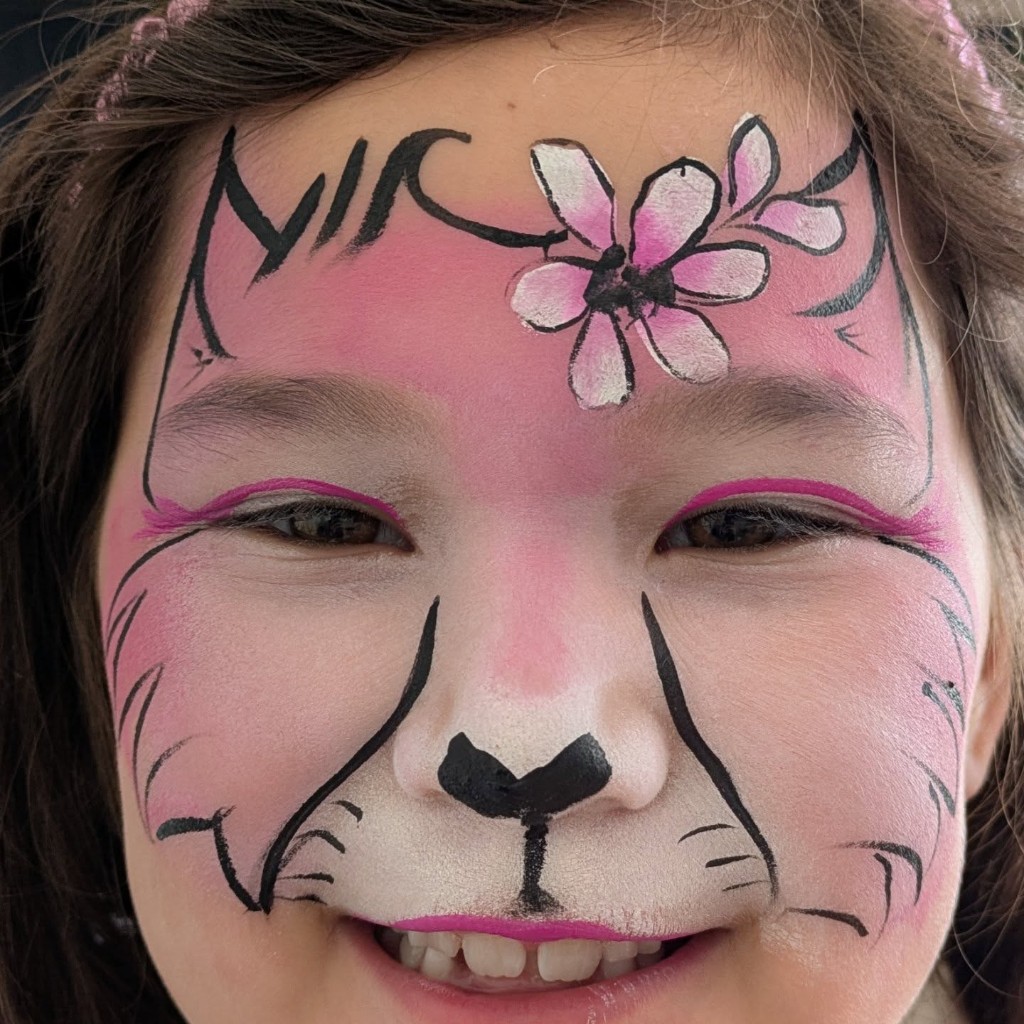 Pink and white cat face paint with whiskers and a flower accent