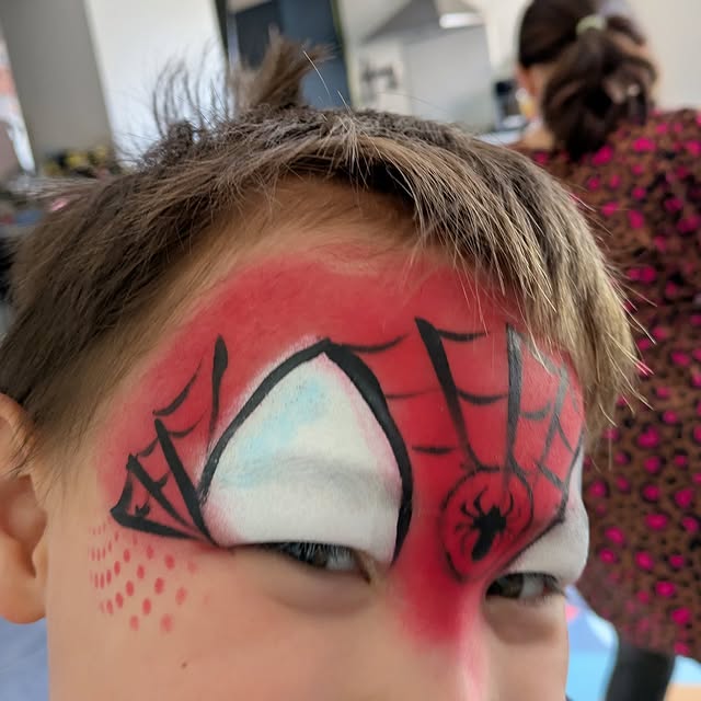 Spider-Man face paint with web pattern and spider detail on a child
